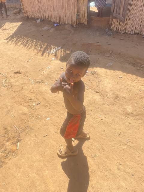 Child making a playful gesture on a sandy path.