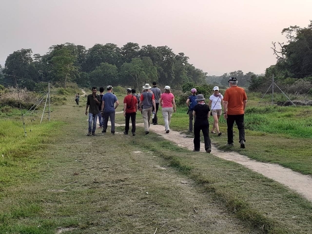 Group of people walking on a dirt path in a natural setting.