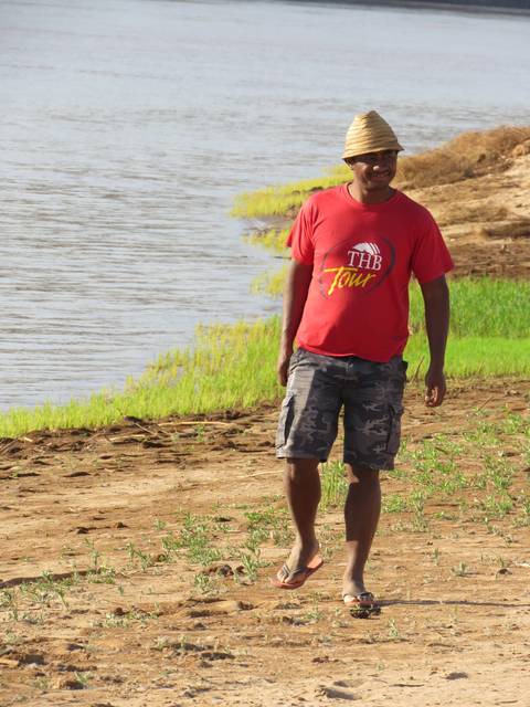       Man standing on a sandy riverside.
  