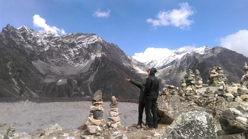       Two hikers pointing towards the mountains in a rocky terrain.
  