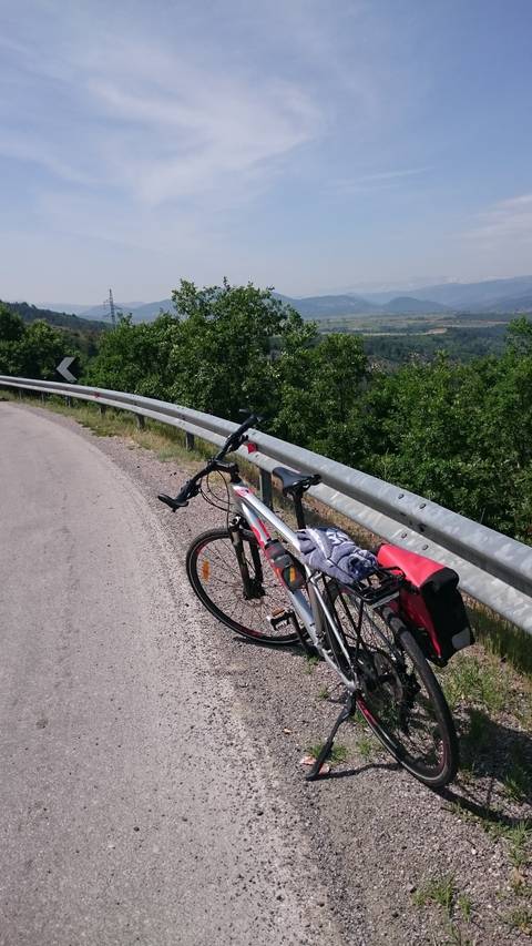       A bicycle leaning against a guardrail with a panoramic view.
  