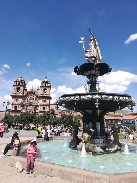 A fountain with a church in the background in Cusco.