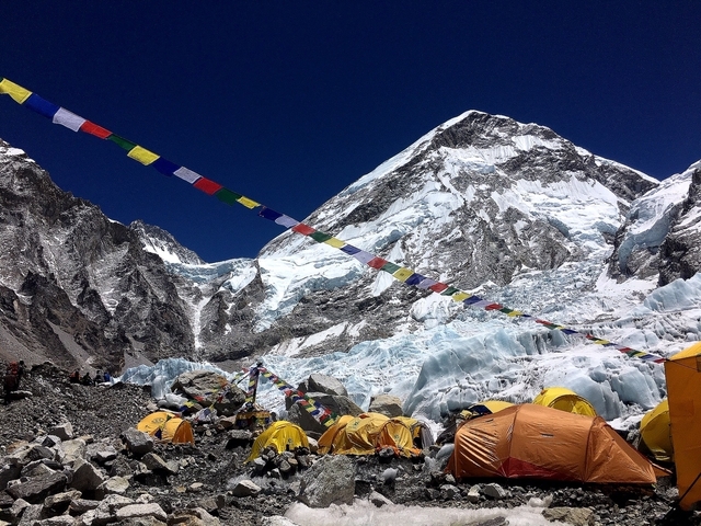 Everest Base Camp with tents and prayer flags against mountains.
