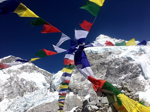 Colorful prayer flags set against snowy mountains.