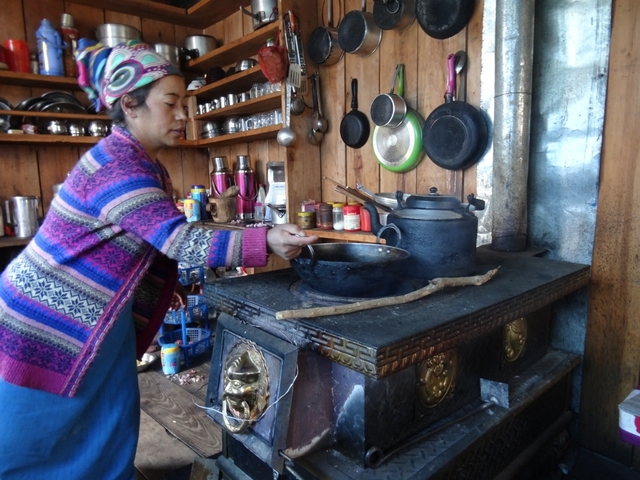       A woman cooking in a traditional kitchen setting.
  