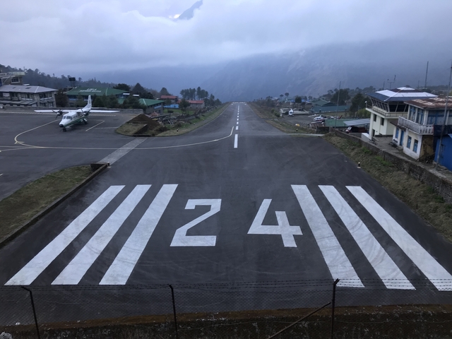       An airport runway leading into the mountains.
  