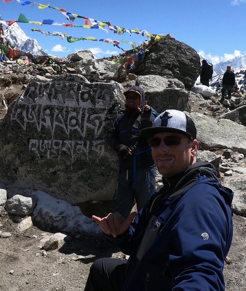       Two people posing next to a rock with carvings.
  