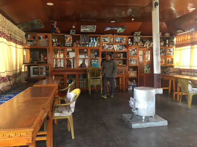       Interior of a teahouse with a person standing, showcasing local memorabilia.
  