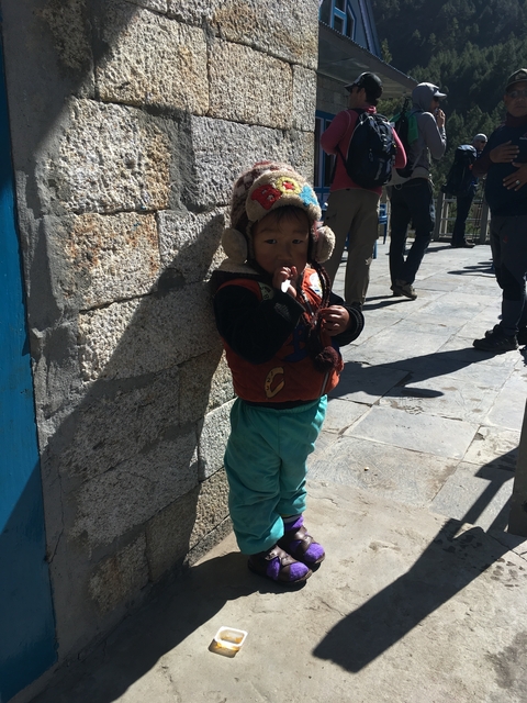       A small child wearing a hat standing against a wall.
  