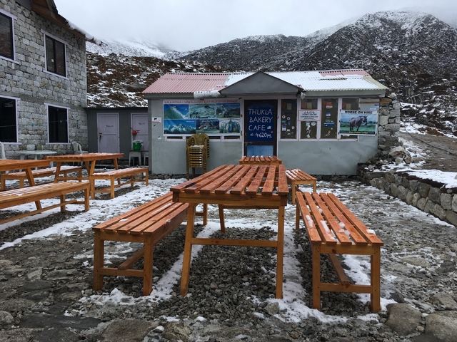       Outdoor eating area with wooden benches at a cafe in a snowy environment.
  