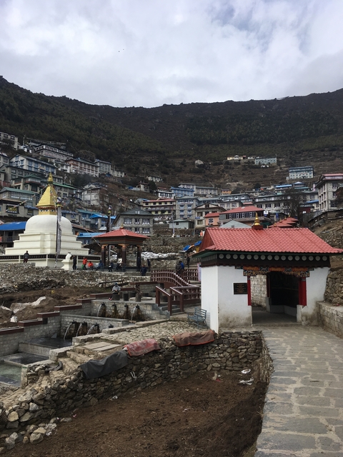       A stupa and homes in a hillside village setting.
  