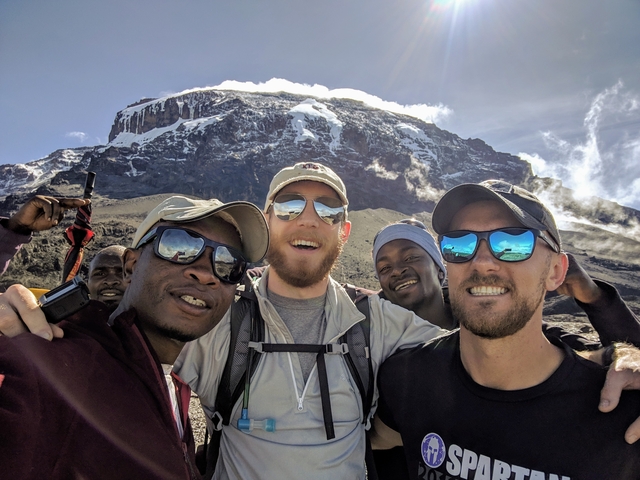       Group of climbers posing in front of Mount Kilimanjaro.
  