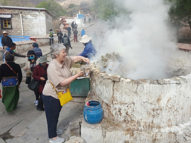 People gathered around a steaming structure outdoors.