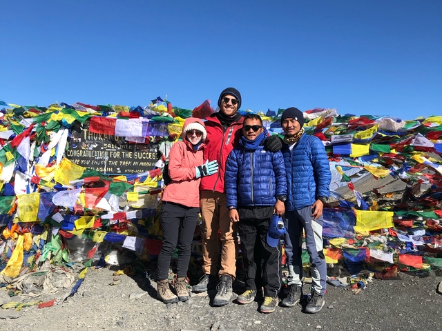       Group of hikers posing with colorful prayer flags
  