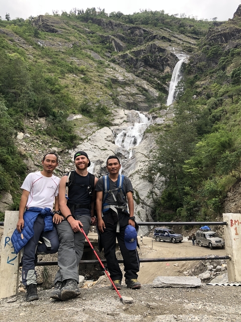       Three trekkers posing in front of a waterfall
  