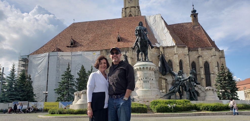 Couple in front of a large historic building with a statue.