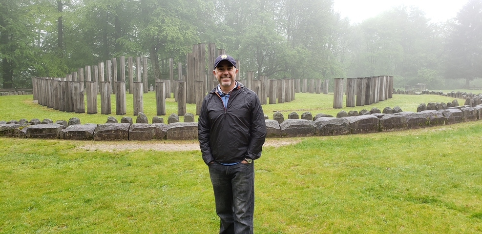 Man standing in front of ancient stone structures.
