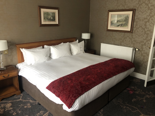 Interior of a hotel room with a large bed and paintings.