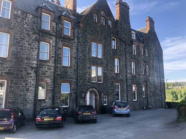 Historic stone building with parked cars.