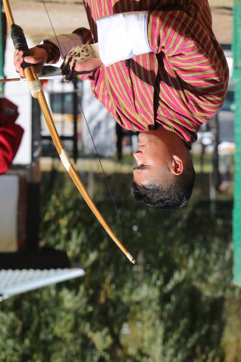       Person practicing archery in traditional attire.
  