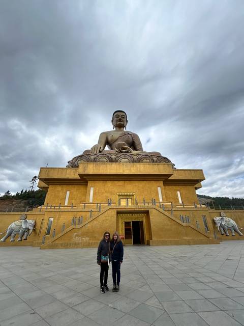       Large golden statue and people posing in front
  