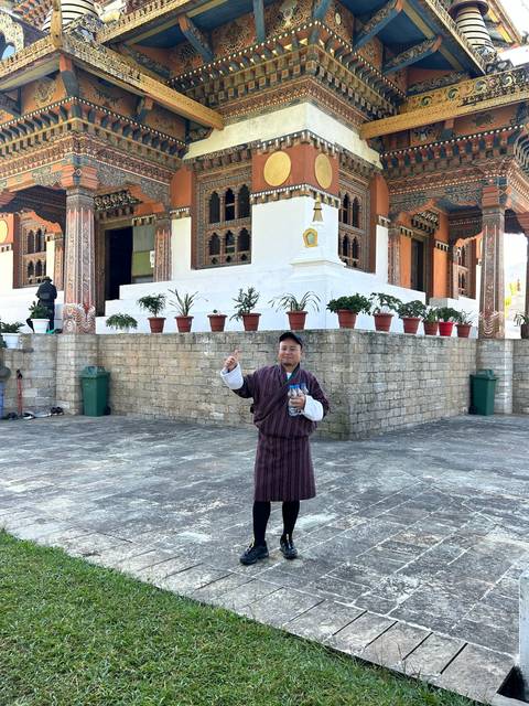       Person in traditional clothing standing outside a temple
  