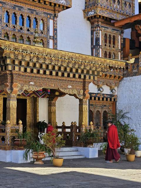 Decorated temple exterior with monks walking.