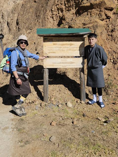 Two people posing beside an information board in a rural area.