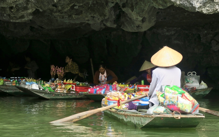 People selling goods on boats in a cave.