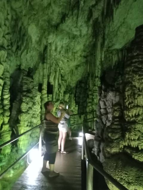       People inside a cave with stalactites.
  