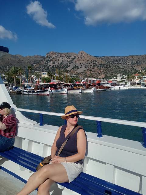       Person on a boat with a view of other boats and mountains in the background.
  