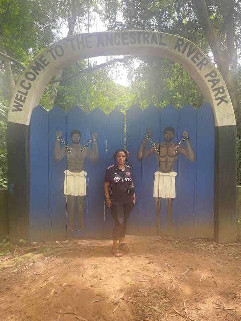       Woman posing under a sign by the river.
  