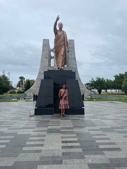       Statue in front of a woman posing.
  