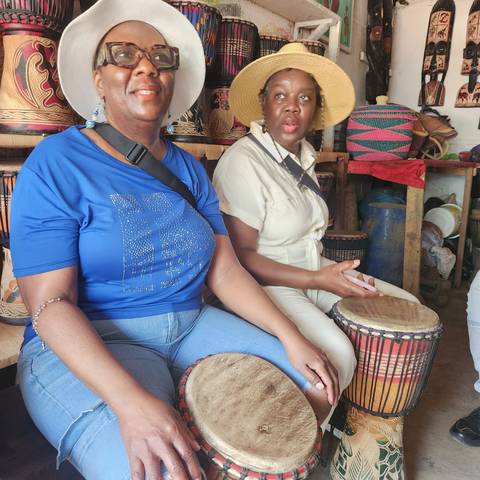       Two people playing drums with colorful clothing.
  