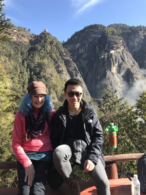 Two people posing in front of a mountain landscape.