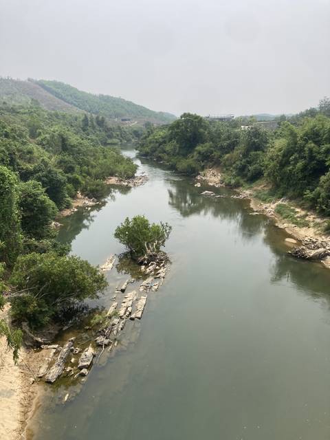       Calm river lined with trees and rocks.
  