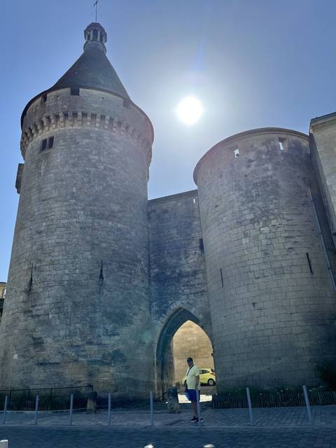 Historic stone building with a bright sun in the background.