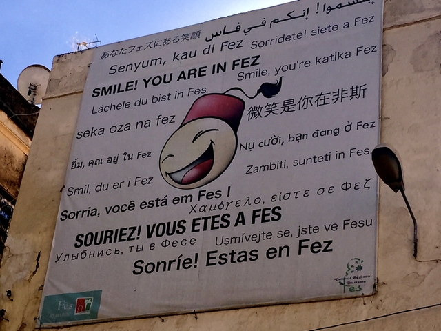       Sign painted on a wall with a smiling face and 'SMILE! YOU ARE IN FEZ' in multiple languages.
  