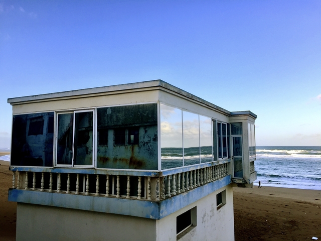       Dilapidated beach house with ocean waves crashing in the background.
  
