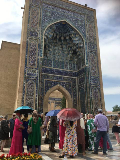 People in colorful clothing outside a decorated historic building.