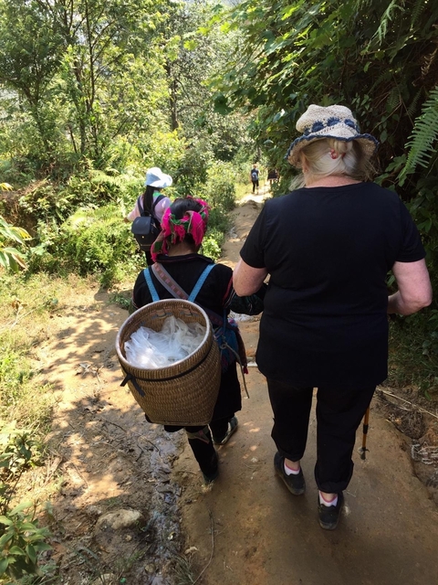 A woman walking with a local carrying a basket.