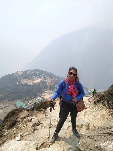 Person hiking on a rocky trail with mountains in the background.