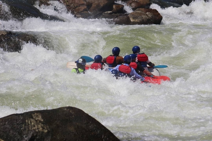 Group of people white-water rafting in rough waters.