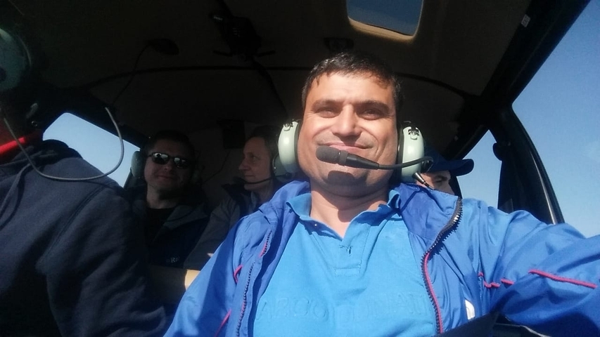 People inside a helicopter smiling for a selfie.