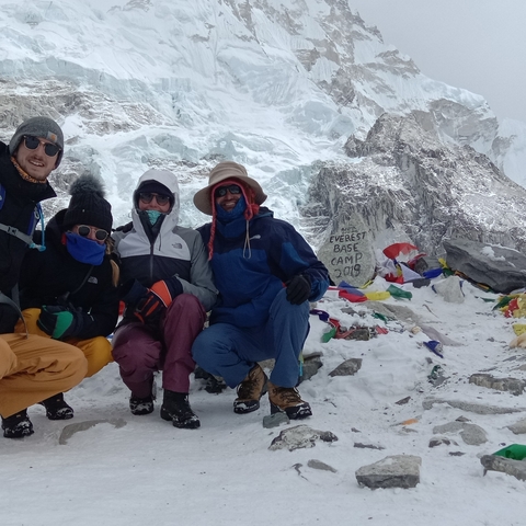 Tourists posing at Everest Base Camp with snowy background.