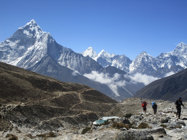 Hikers walking towards snow-capped mountains.