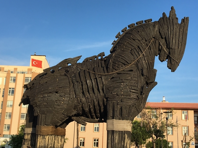 A large wooden horse sculpture with a Turkish flag in the background.