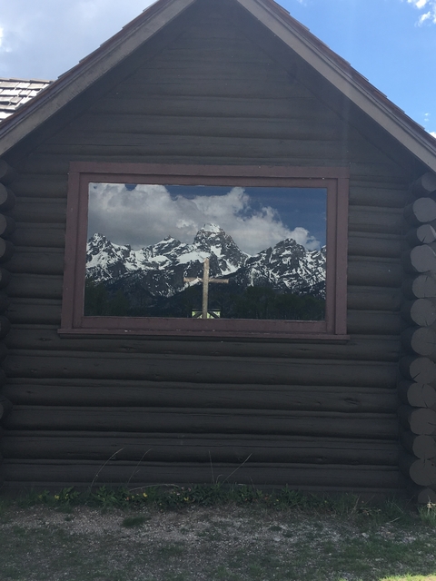 Mountain peaks reflecting in a wooden window frame.