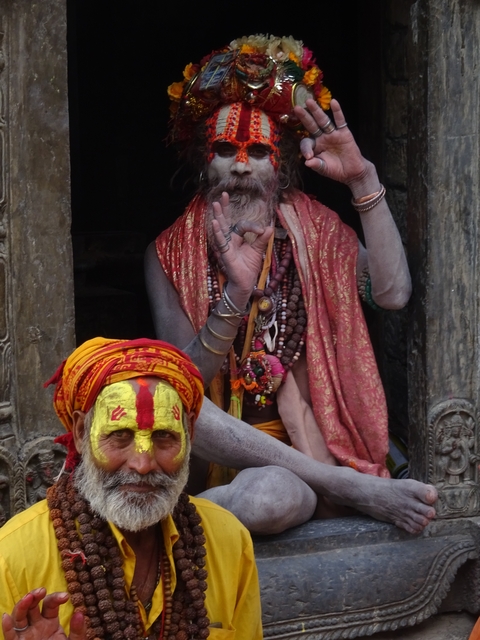 Two people in colorful attire sitting outside a temple.
