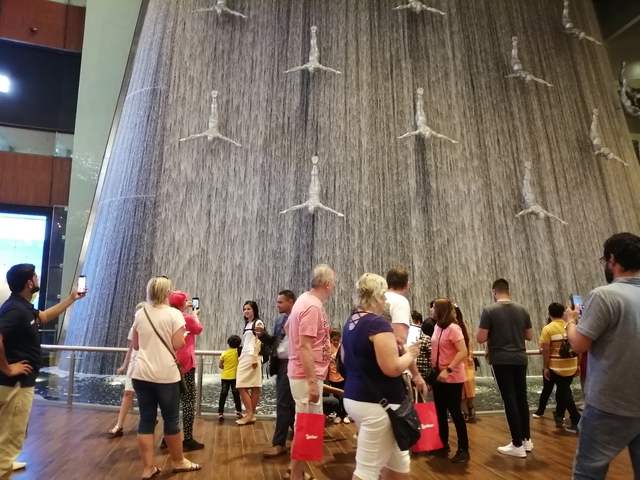 Indoor waterfall with people taking photos.